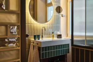 Juniorsuite Ein Badezimmer mit rundem Spiegel und Waschbecken.