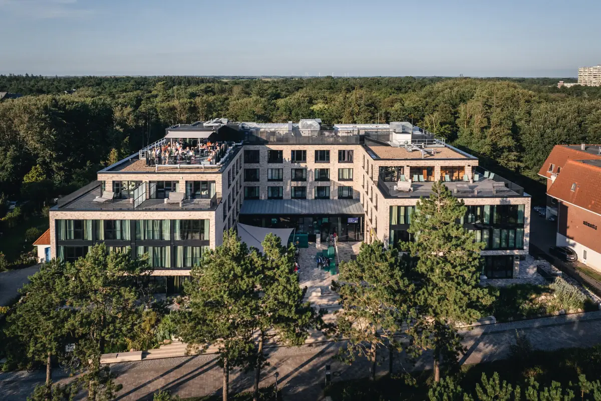 Urban Nature St. Peter-Ording Das Urban Nature Hotel in St. Peter-Ording mit Bäumen im Hintergrund.