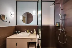 Juniorsuite Straubinger Platz mit Sauna Badezimmer mit Dusche und Waschbecken, ausgestattet mit modernen Armaturen und einem Spiegel.