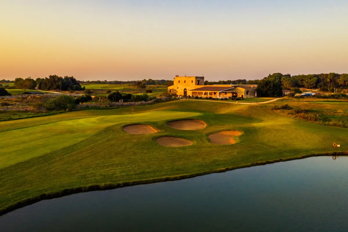 Acaya Golf Resort & Spa Ein Haus steht hinter einem Golfplatz bei Sonnenuntergang.